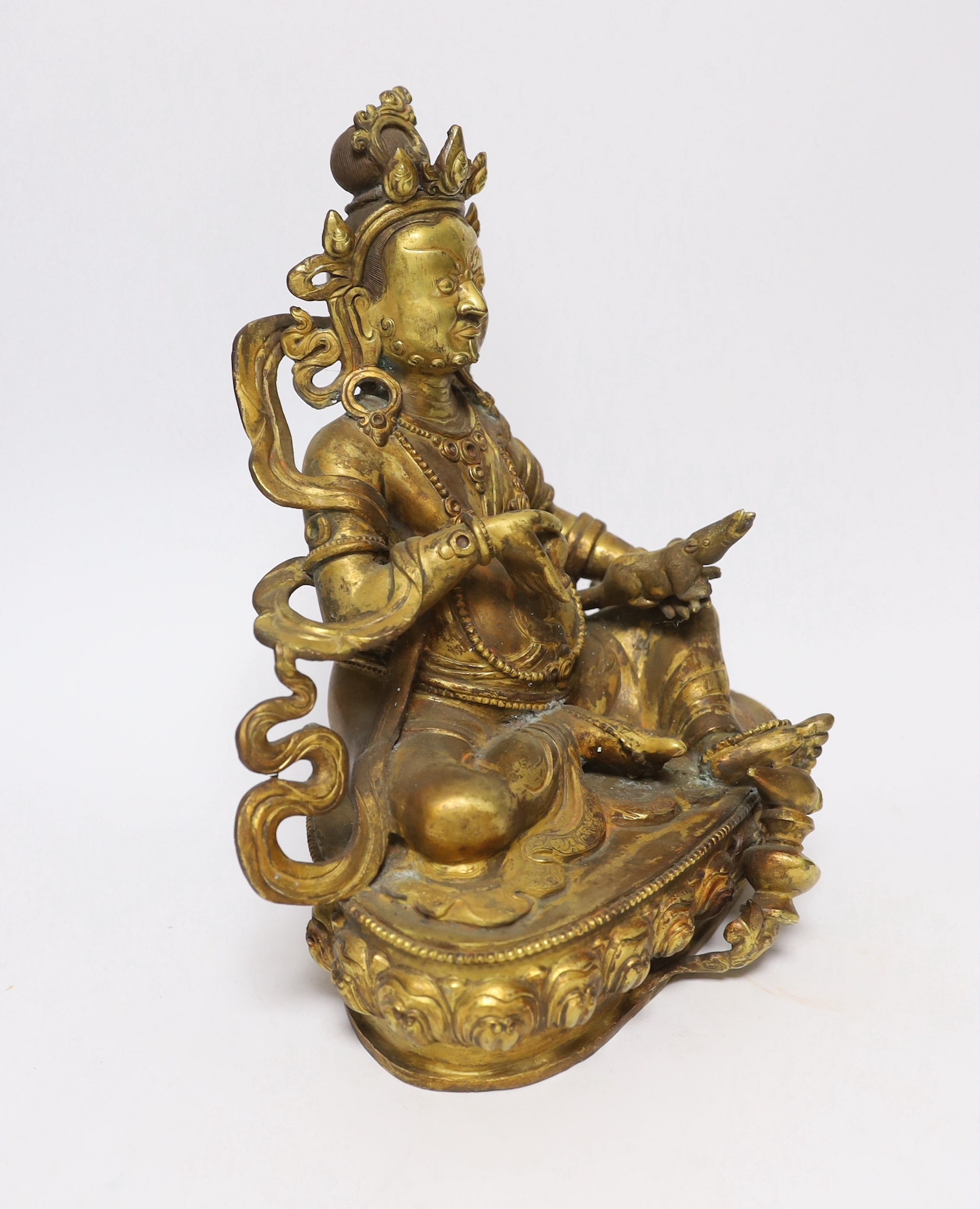 A large Sino-Tibetan gilt bronze seated figure of Jambhala, 28cm high